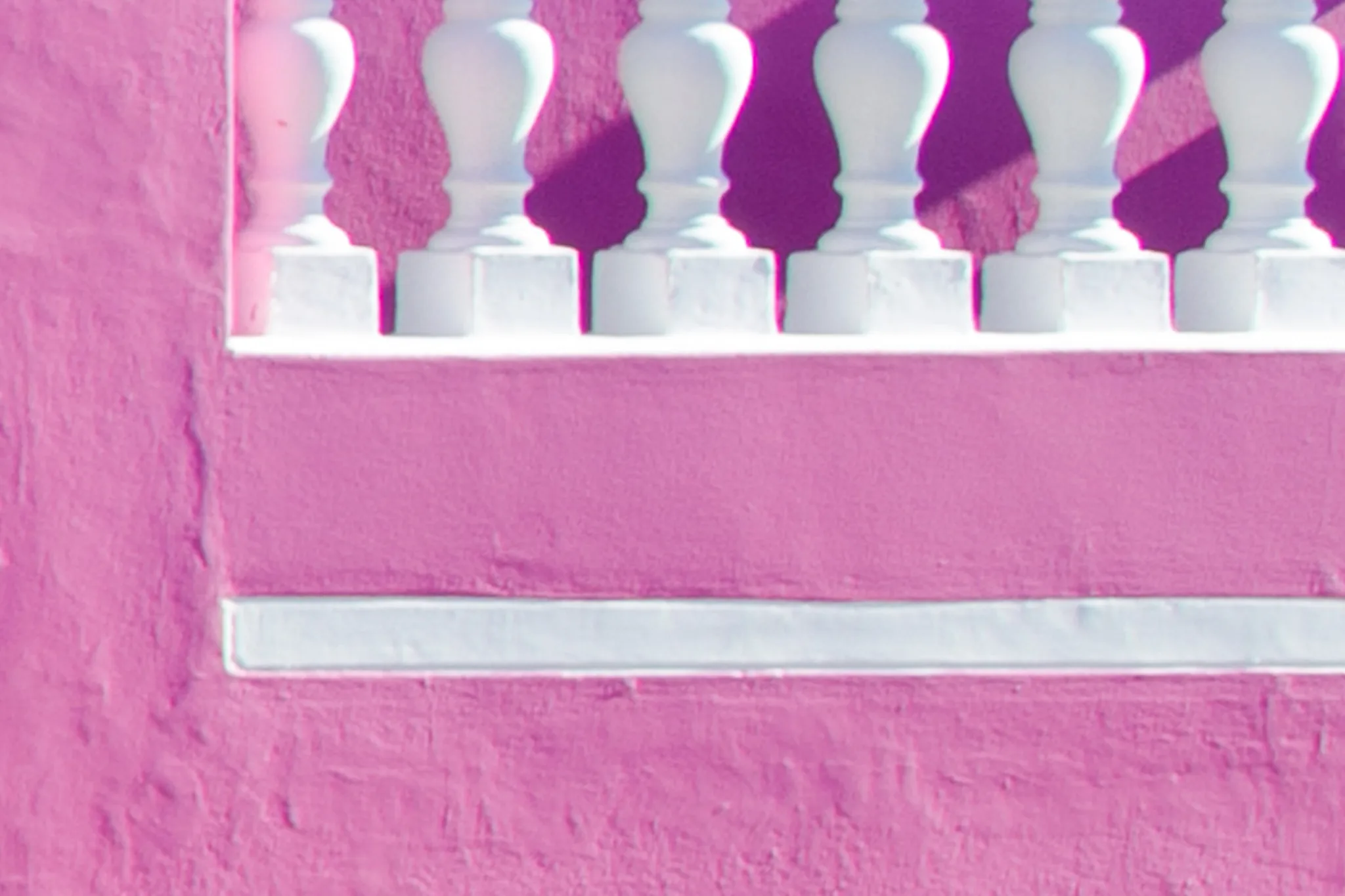 Balaustra bianca su un muro rosa acceso con ombre nette Balaustra bianca su un muro rosa acceso con ombre nette
