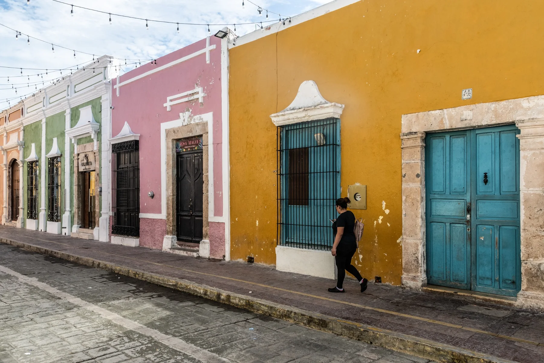 Facciate colorate lungo una strada del Messico con una donna che cammina