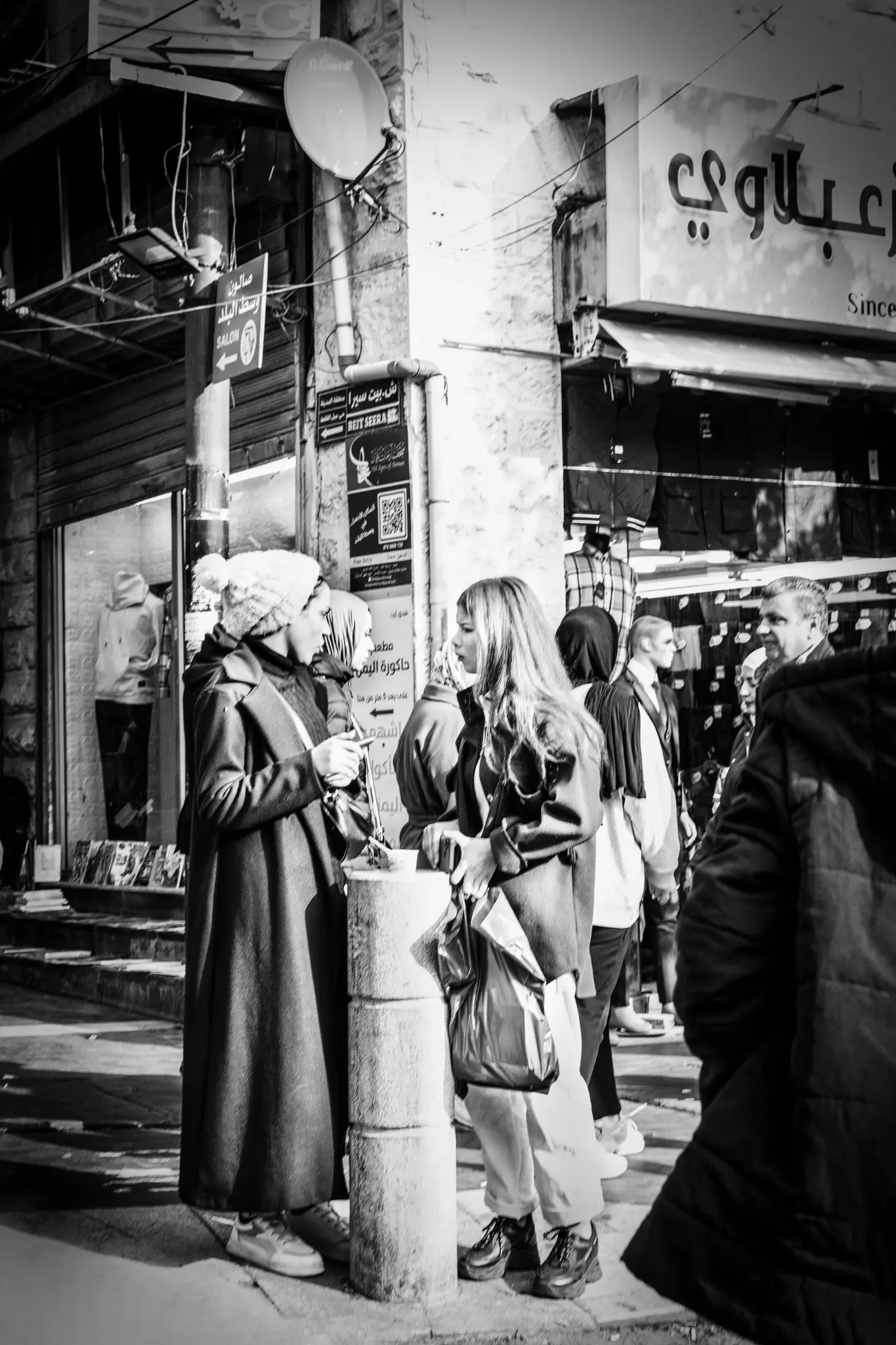 Due giovani donne conversano in una strada affollata di Amman.