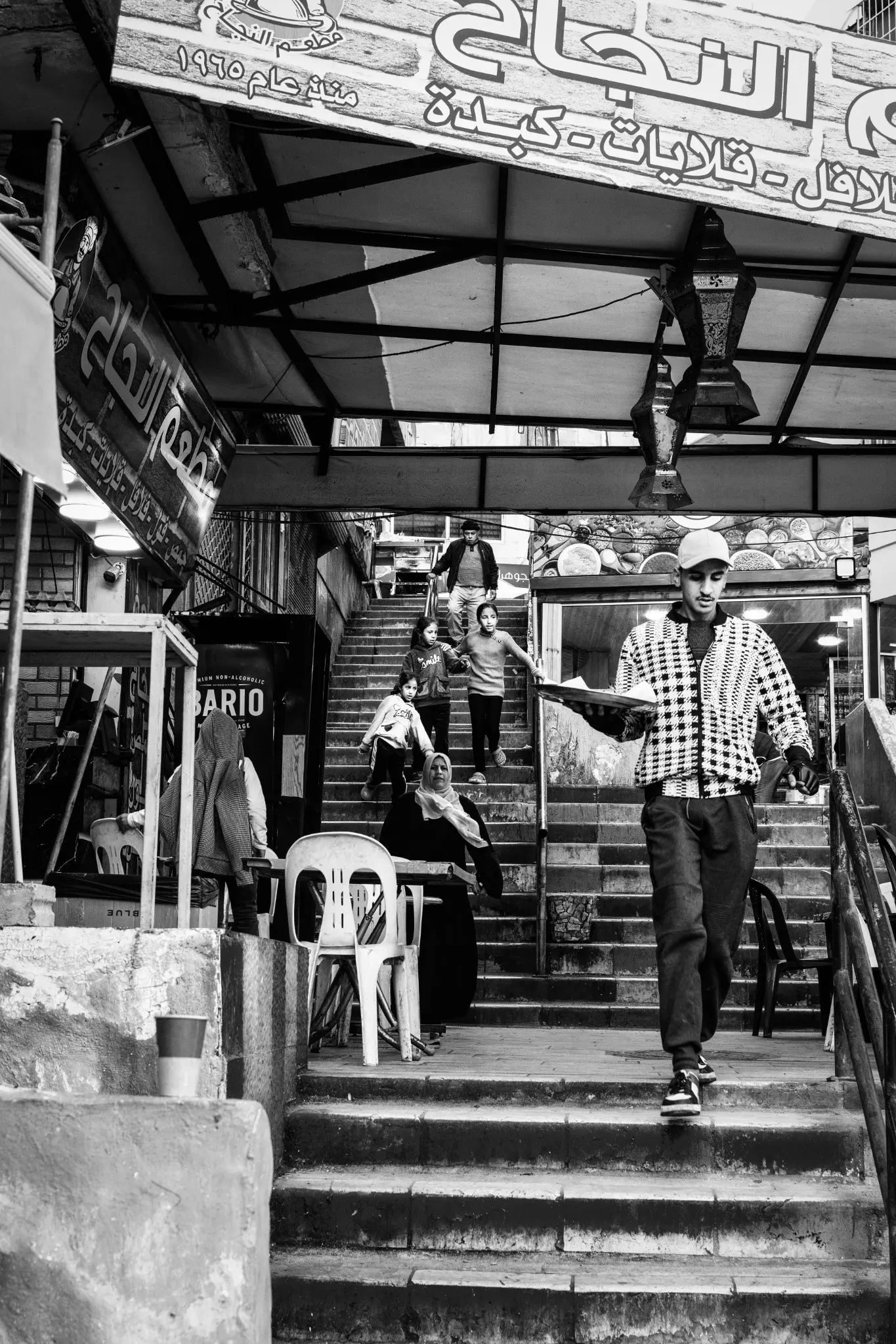 Un giovane cameriere e una famiglia scendono le scale di un mercato di Amman.