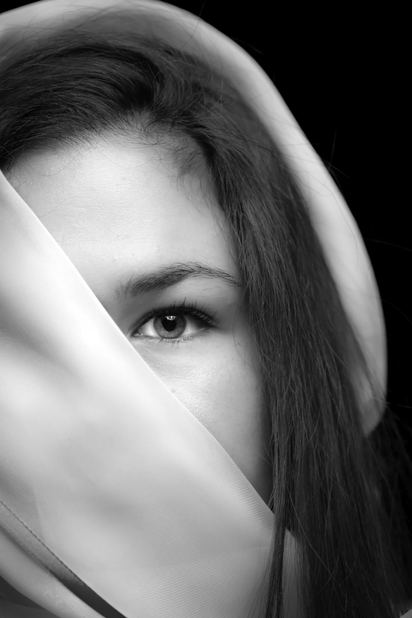 Ritratto in bianco e nero di una donna con un occhio visibile dietro un velo chiaro.