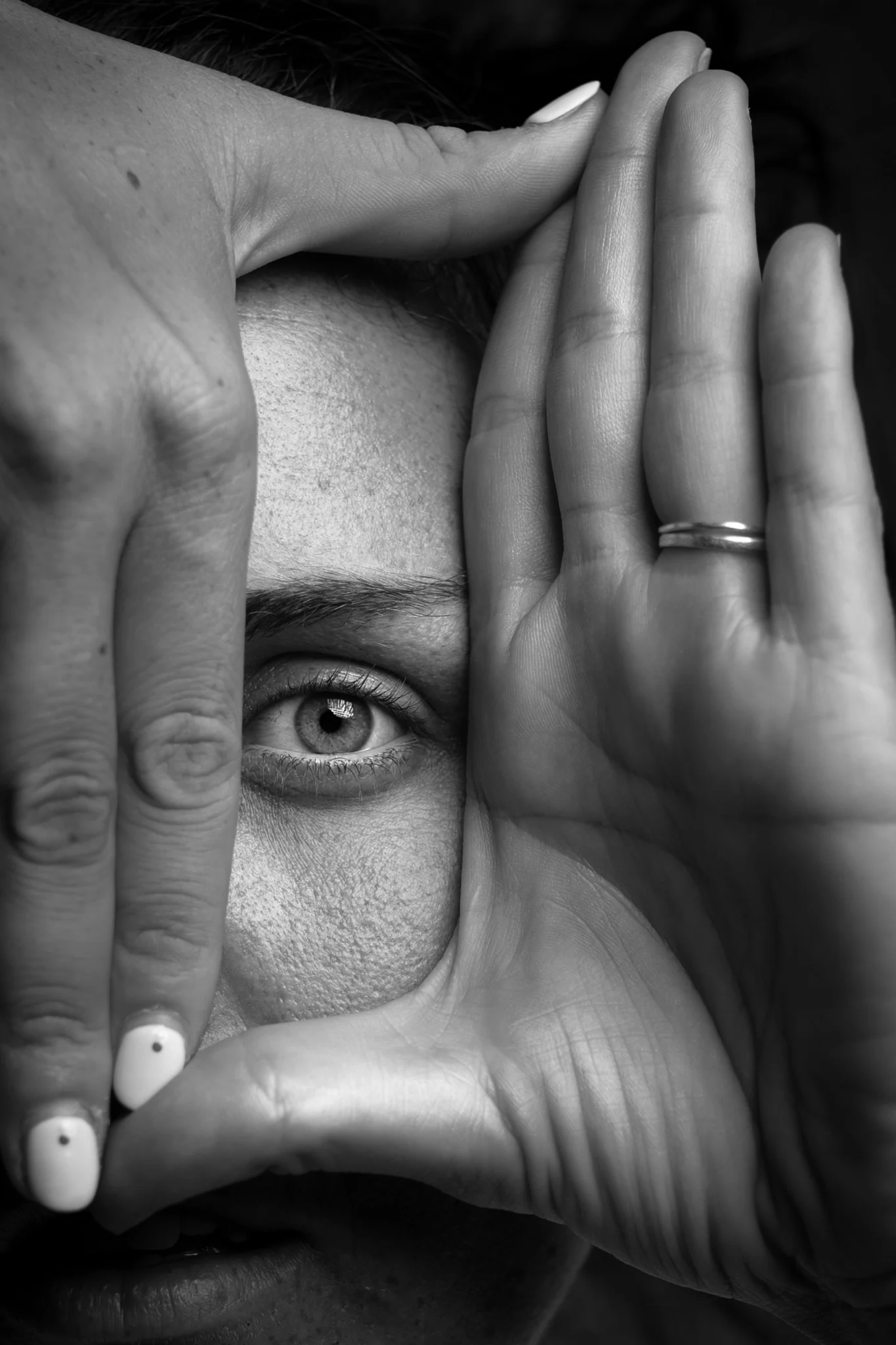 Ritratto in bianco e nero di una donna che incornicia un occhio con le mani.