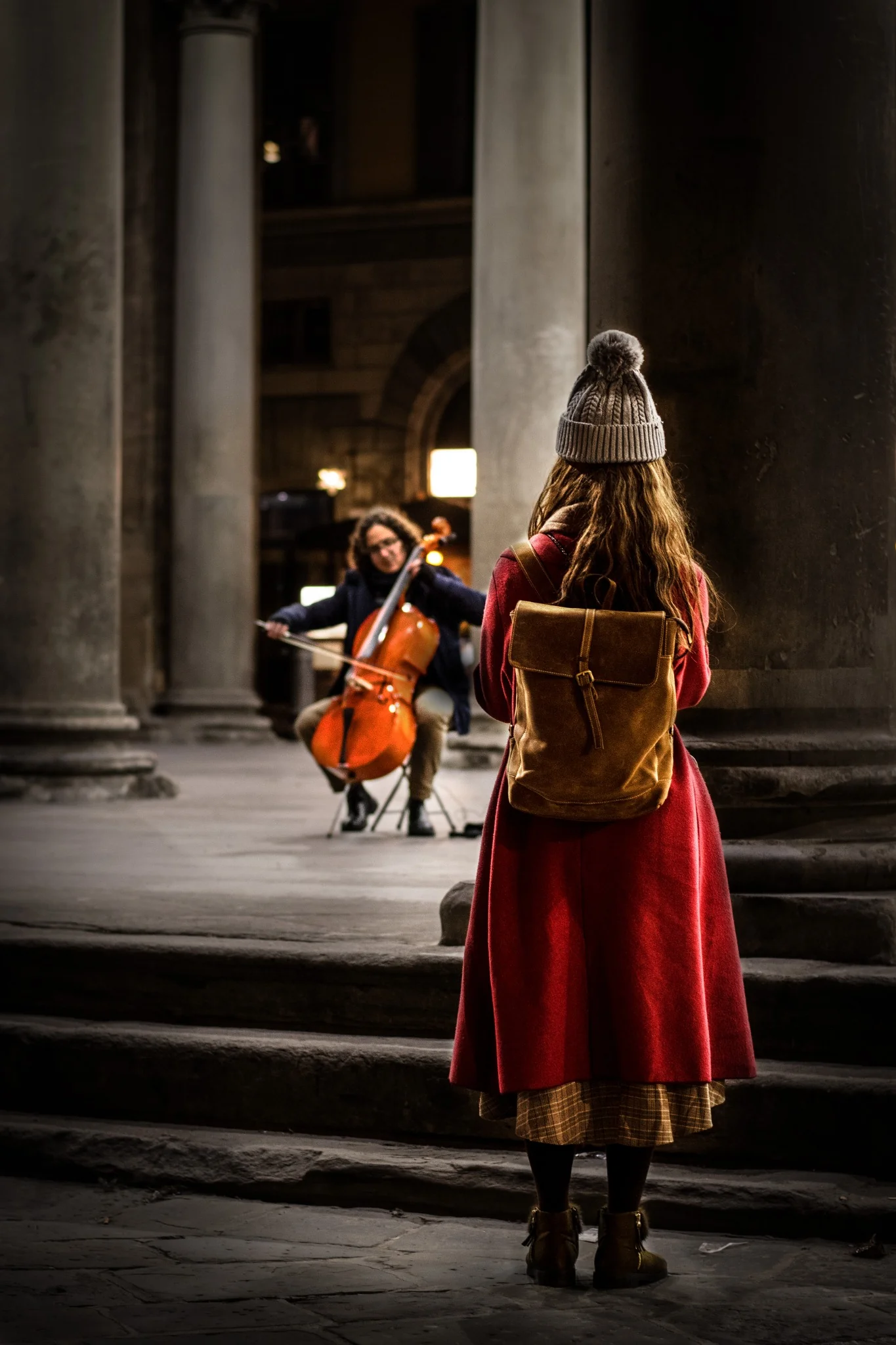 Una figura osserva in silenzio un’opera d’arte rossa in uno spazio espositivo.