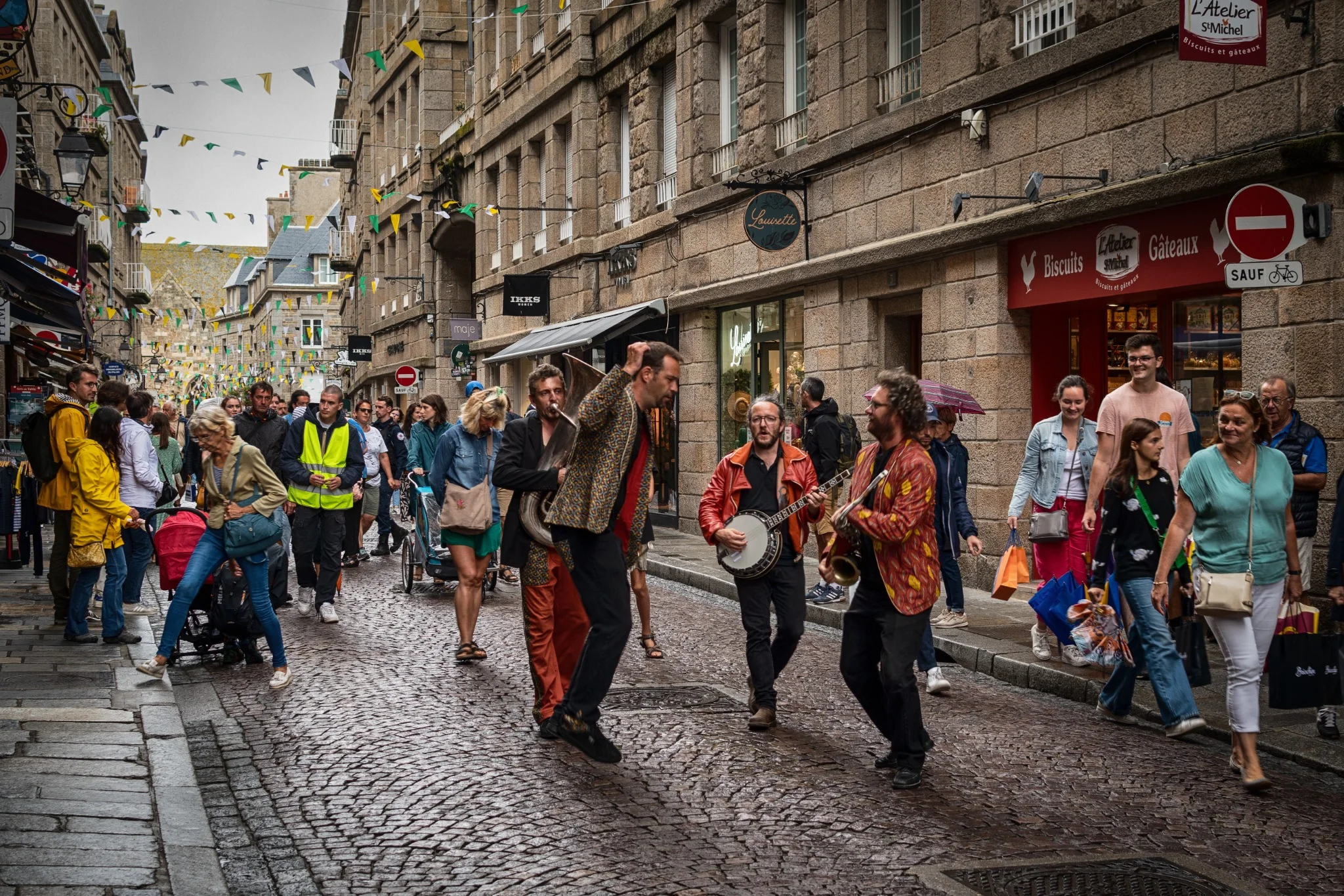 Musicisti di strada e passanti riempiono di movimento una via di Saint-Malo.