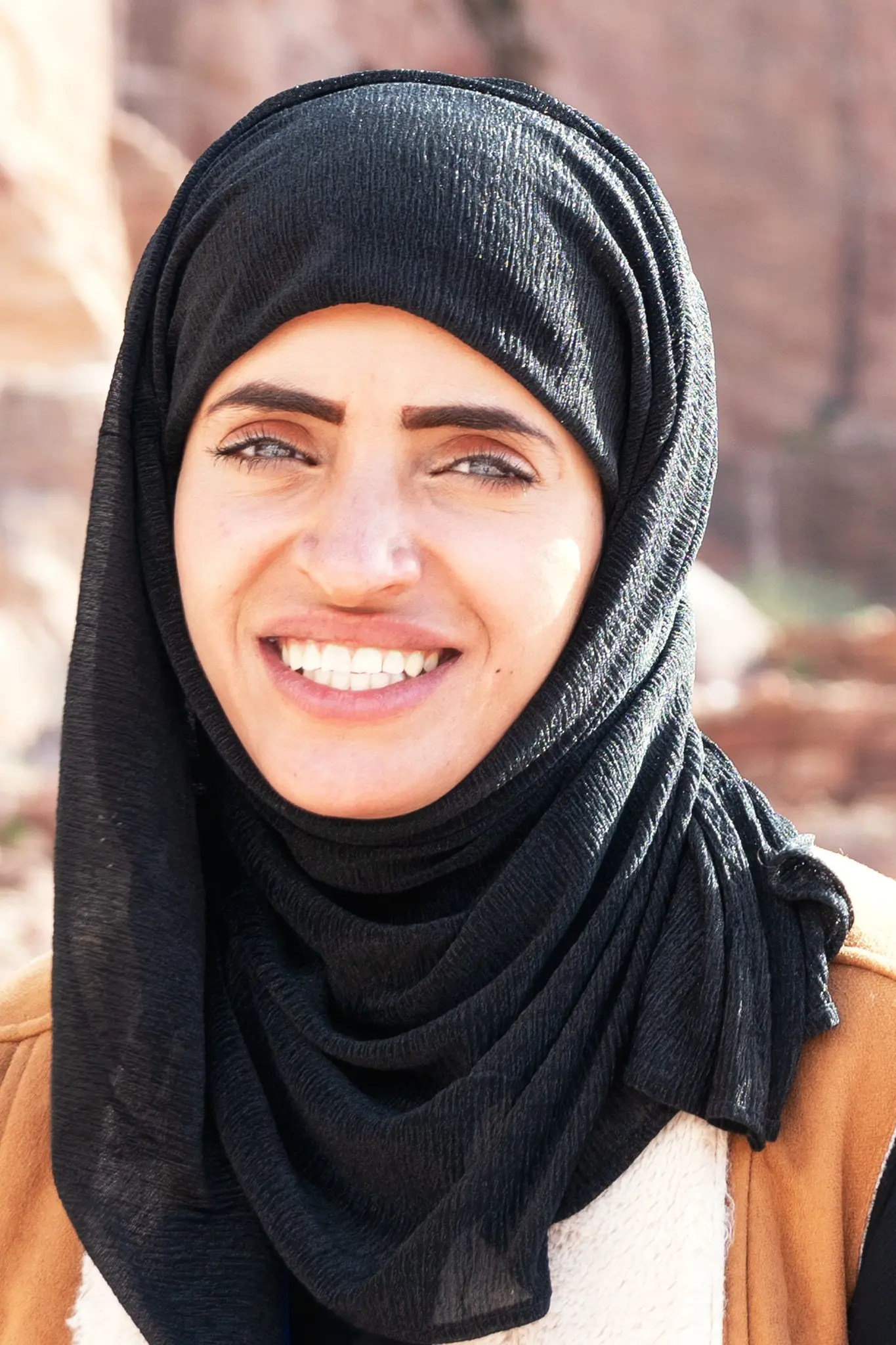Ritratto di una donna sorridente con velo nero a Petra, in Giordania.