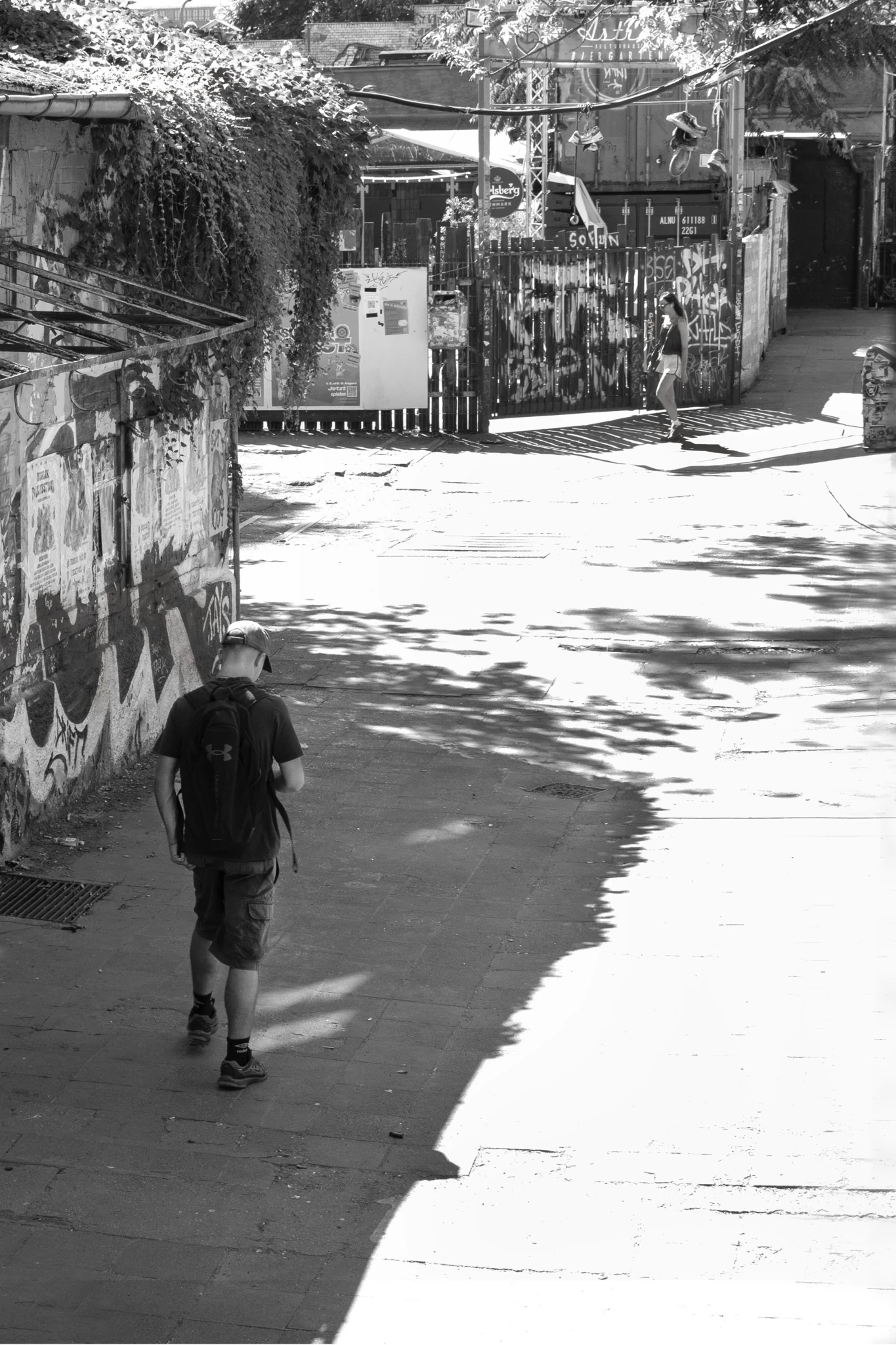 Una figura cammina in un passaggio urbano tra ombra e luce