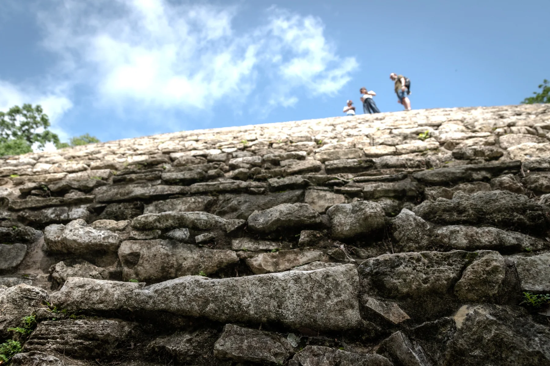 Rovine maya viste dal basso con tre persone sul bordo superiore