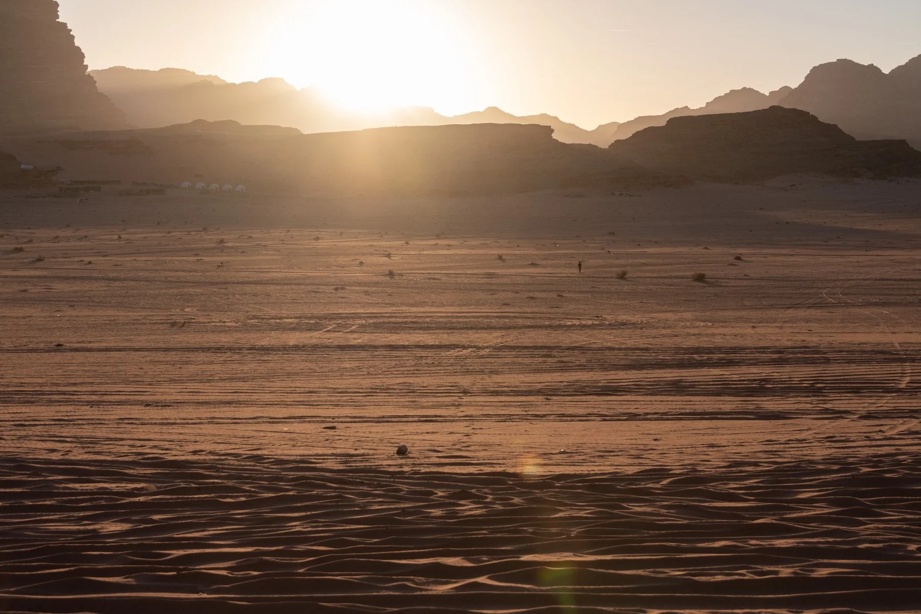 Una figura osserva il tramonto nel deserto del Wadi Rum
